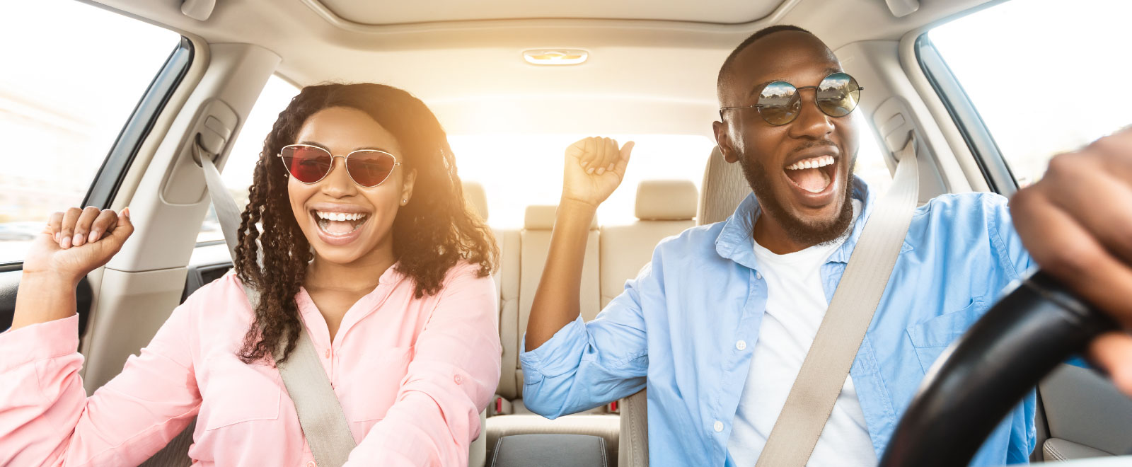 A man driving a car with a woman in the front seat and they are both excited. 