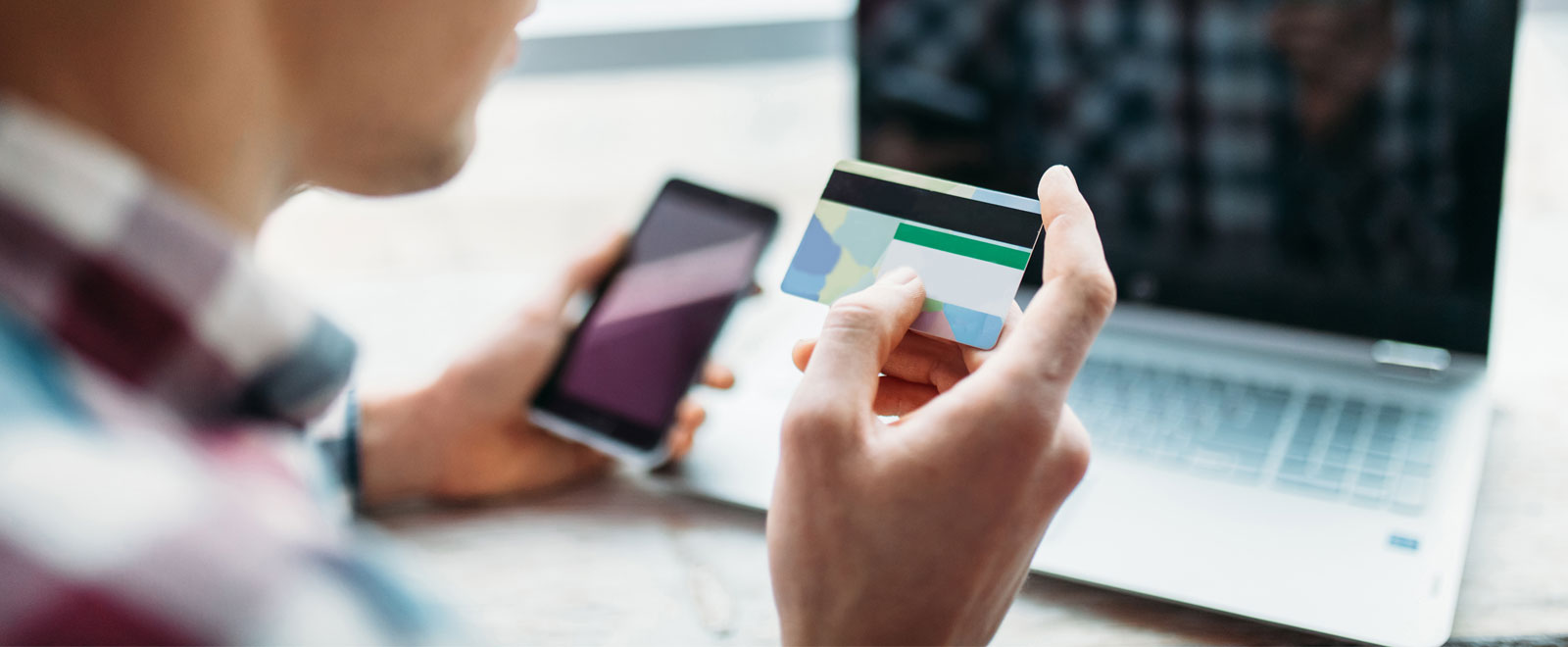 Someone reading off credit card information while holding a phone and sitting in front of a laptop.
