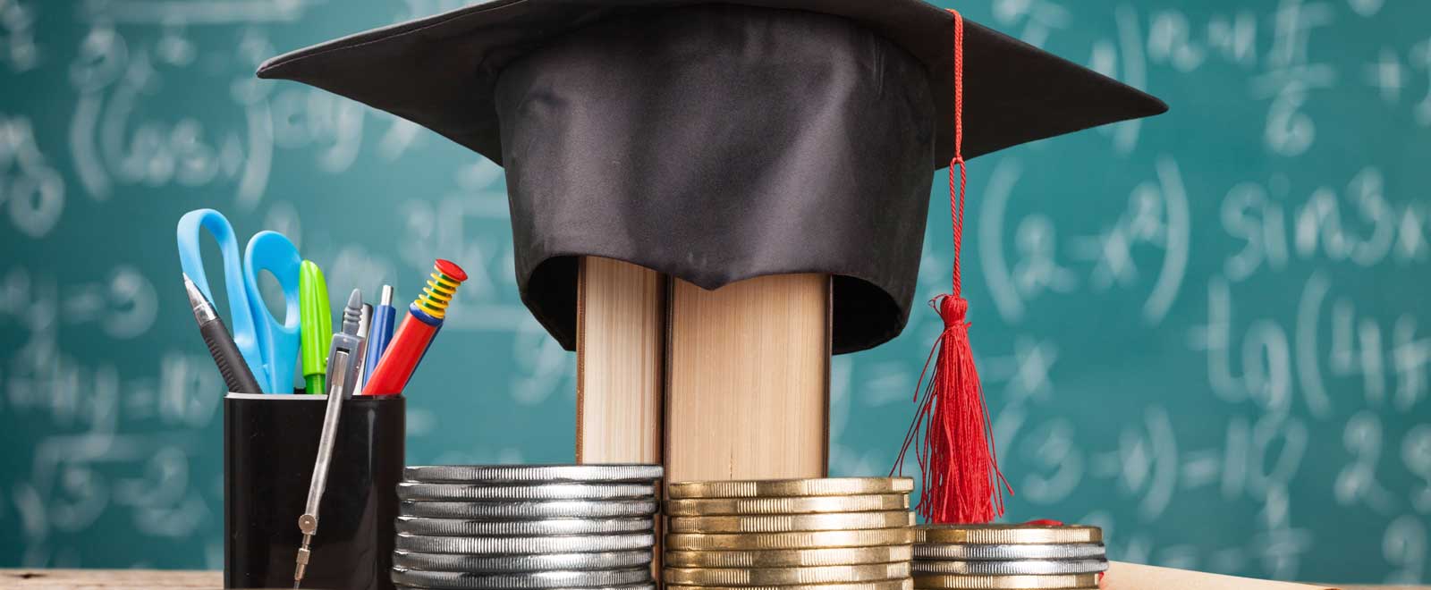 A graduation cap on top of books with other school supplies surrounding it.