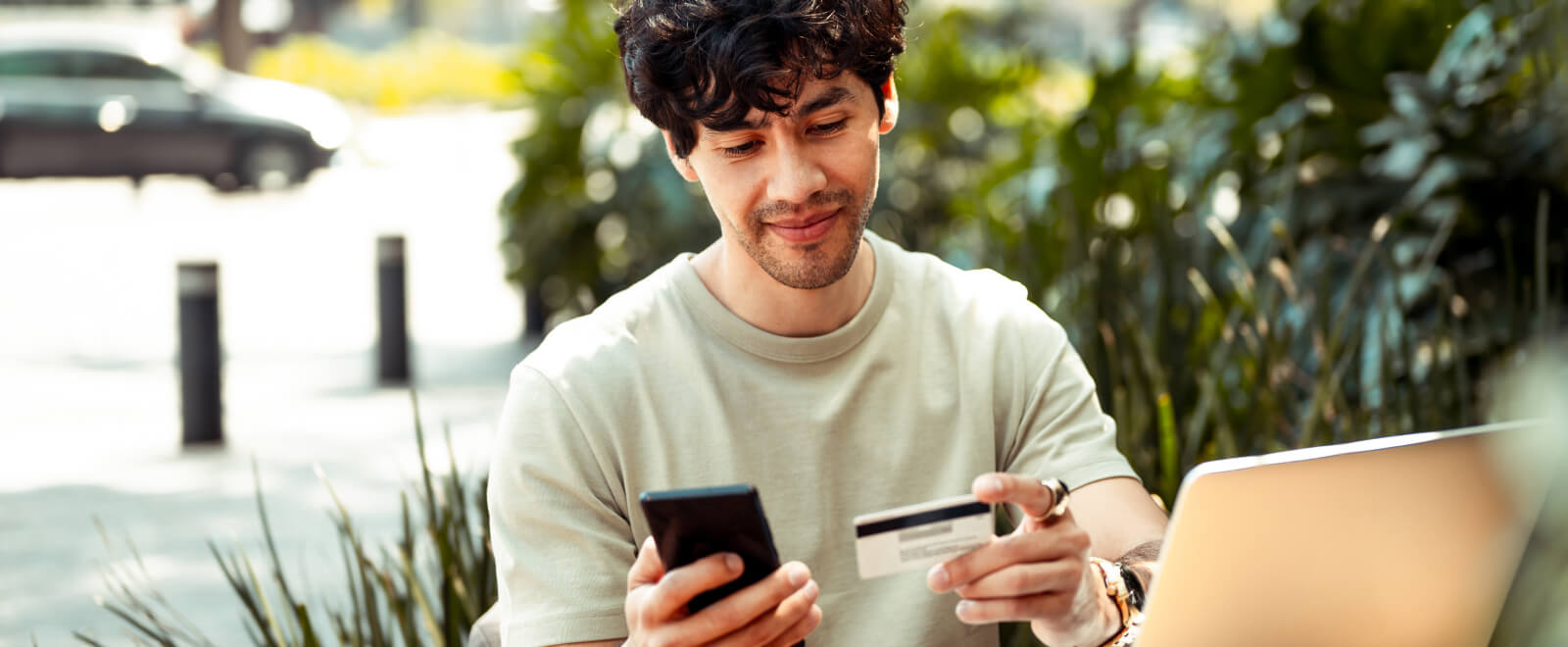Young guy holding phone and credit card.