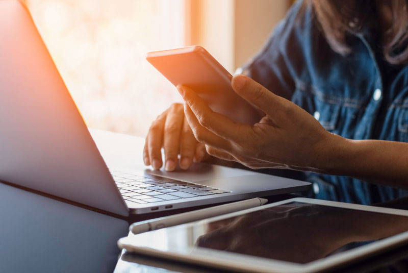 person using laptop, cell phone and tablet