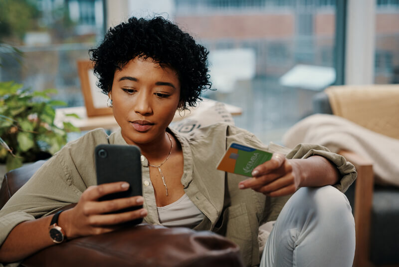 woman holding KEMBA credit card and using cell phone