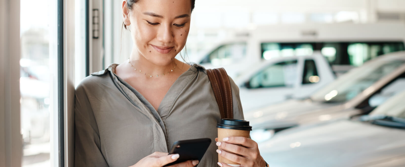 Young woman looking at her phone while in an car dealership.