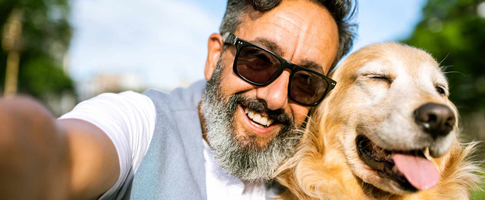 Older gentleman relaxing outdoors with his dog on a summer day, reflecting a sense of ease supported by a KEMBA money market account.