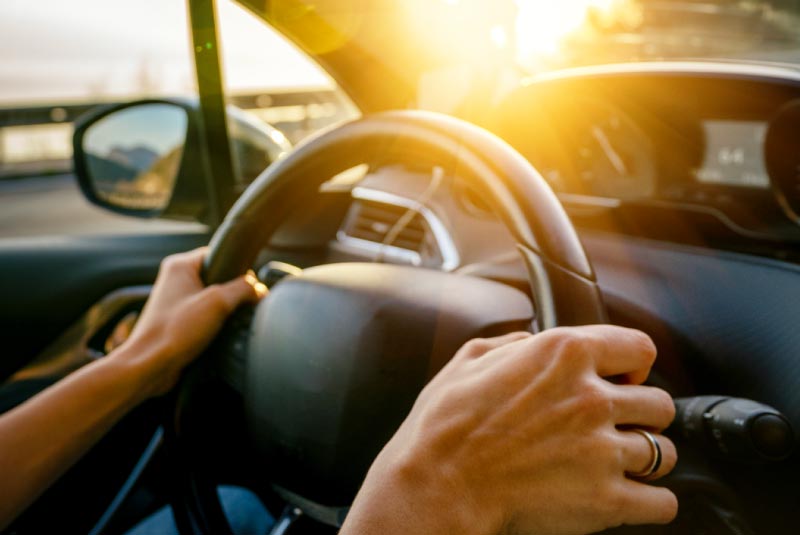 Woman driving confidently after a KEMBA auto loan refinance