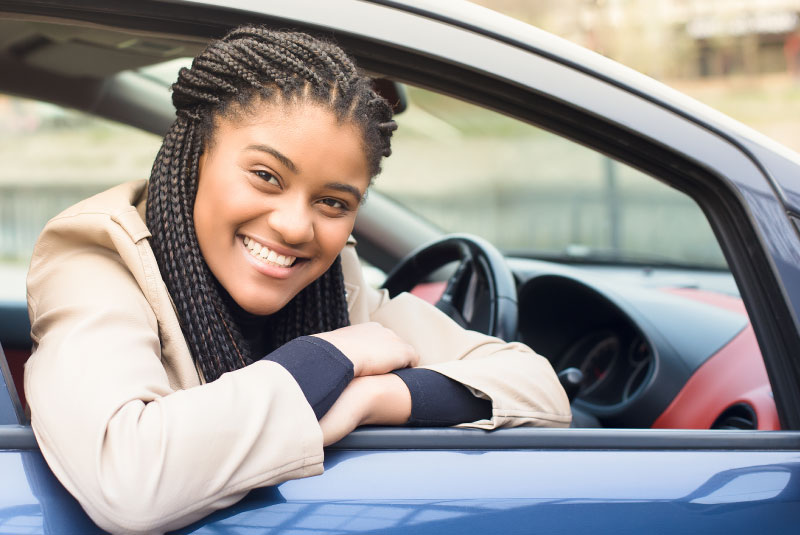 A girl smiling out the window of a car.