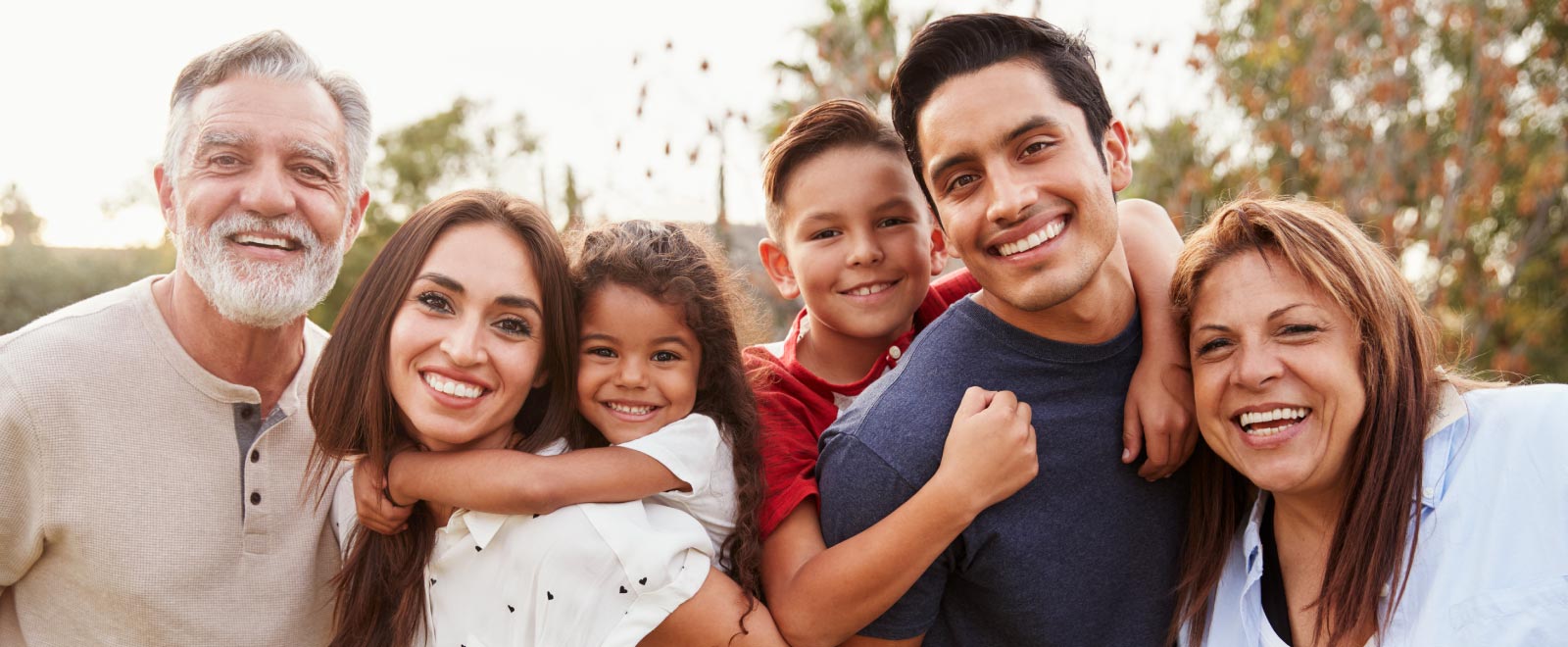 A family of six people close to each other smiling at the camera.