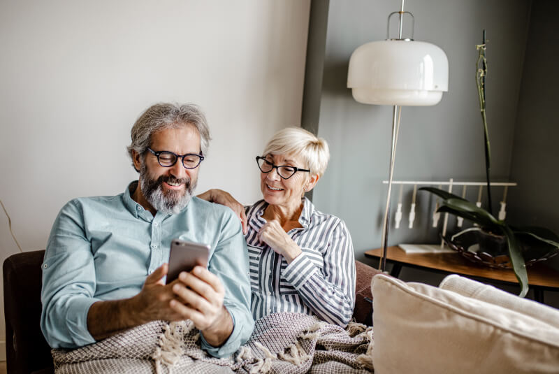 mature couple smiling and using cell phone