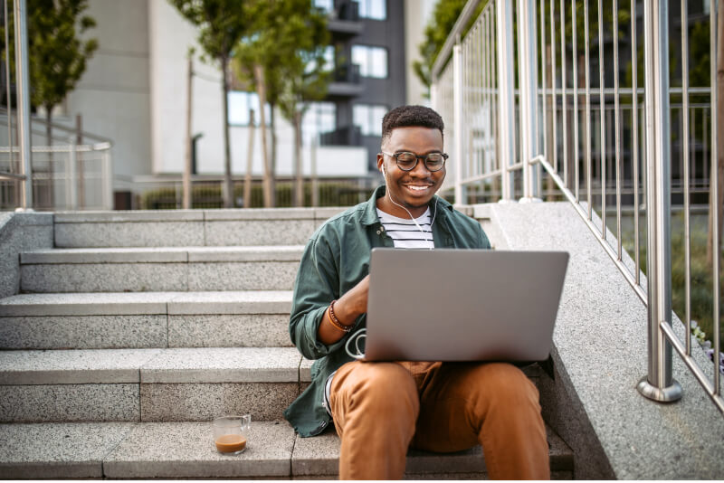 happy young man using laptop outside