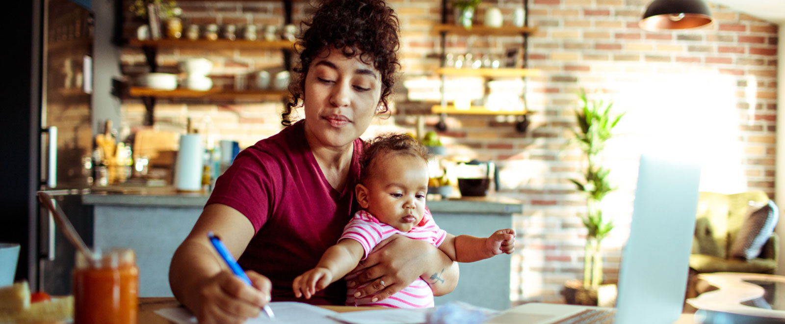 young mother holding infant while working