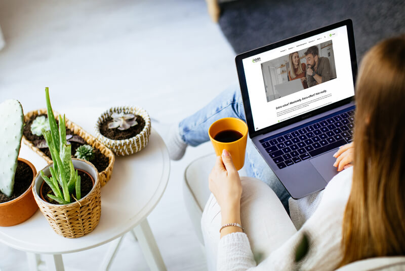 Woman with coffee in hand looking at KEMBA website on computer.