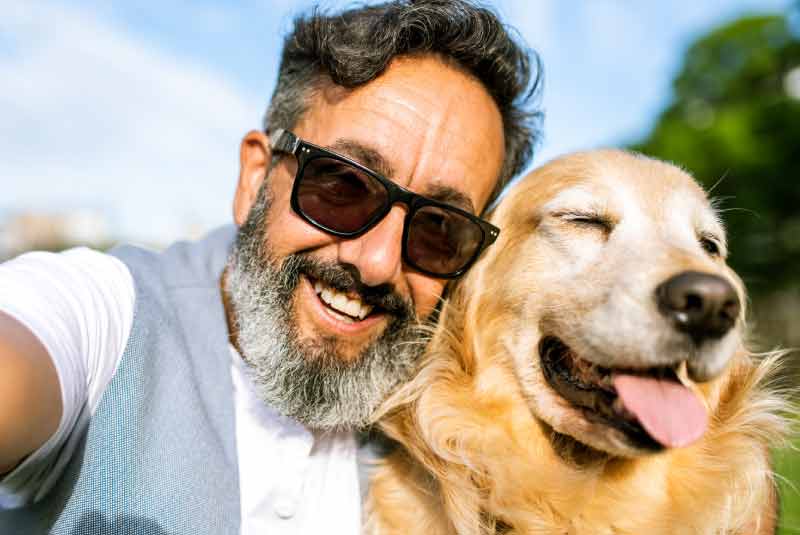 Older gentleman relaxing outdoors with his dog on a summer day, reflecting a sense of ease supported by a KEMBA money market account.