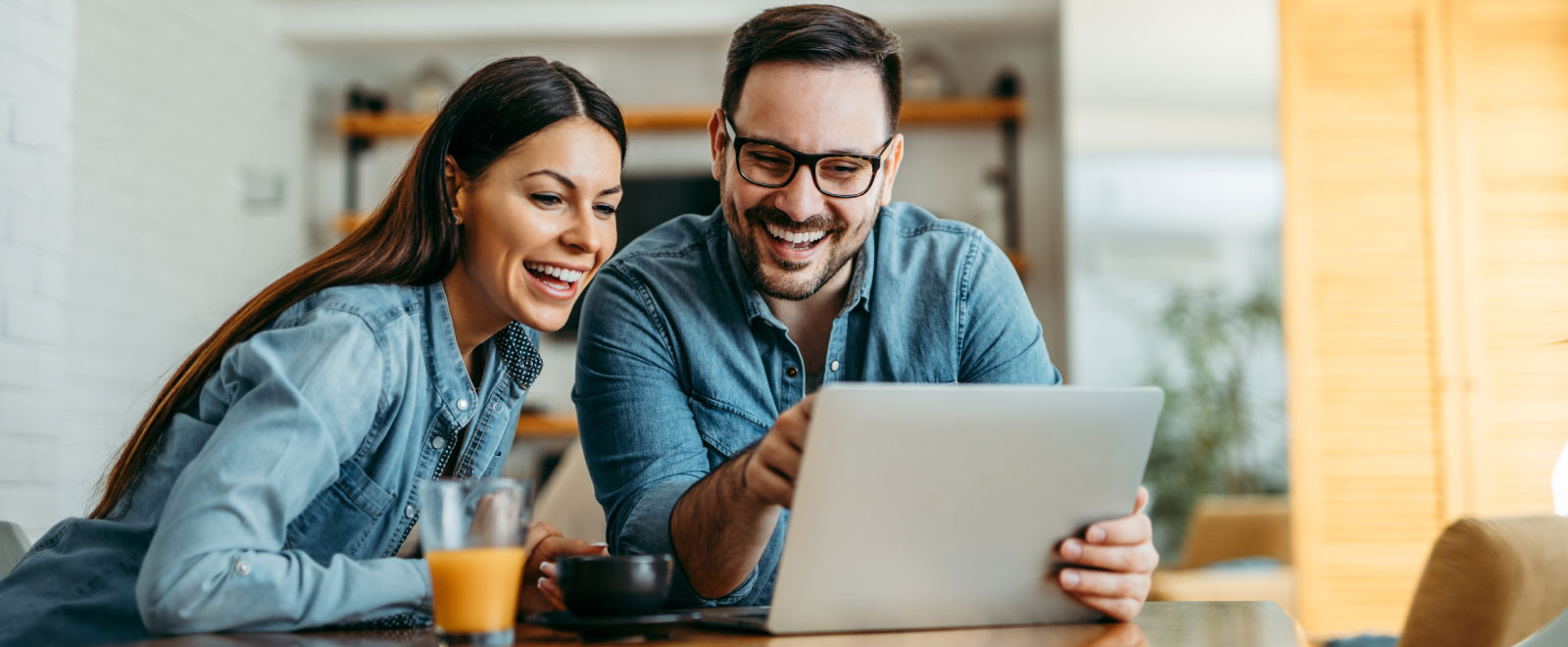 couple smiling and using computer during breakfast