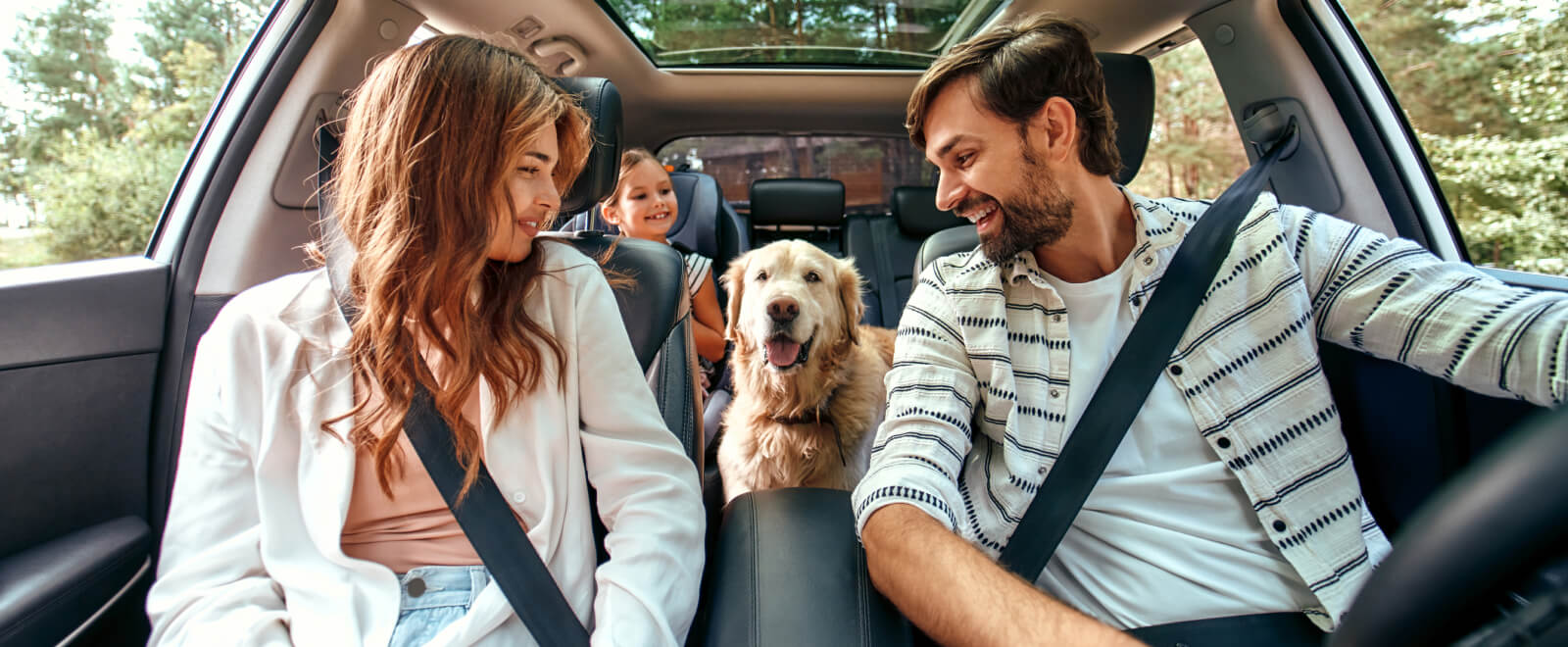Young family and dog in the car for a road trip.