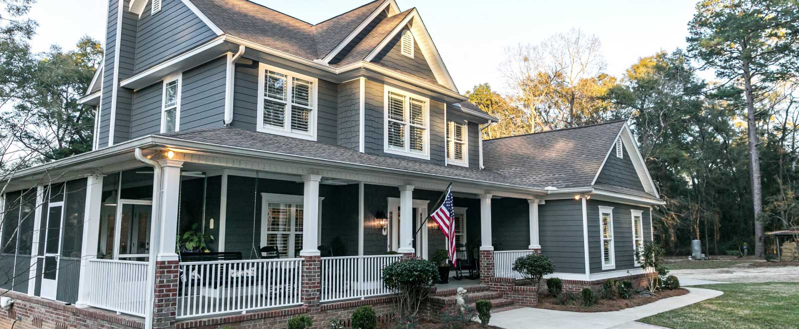 A large blue home with a wrap around porch.
