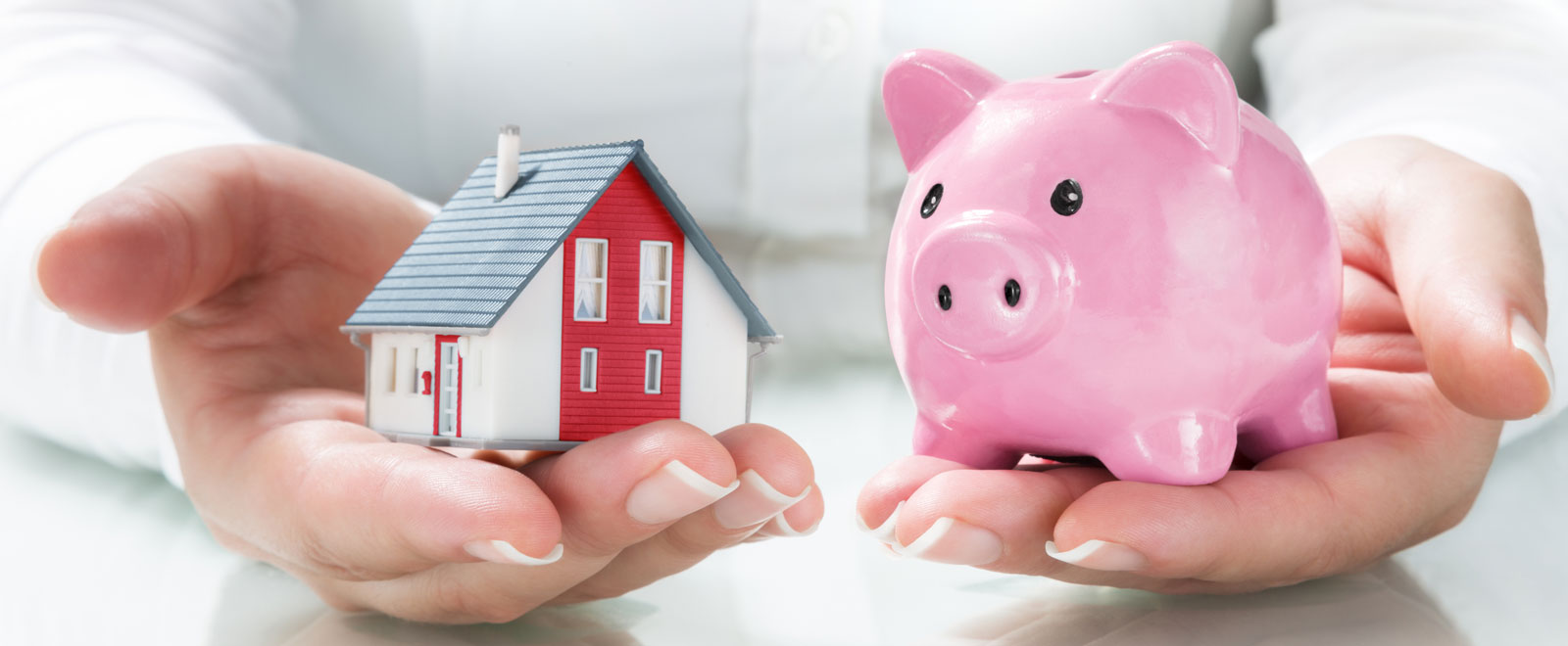 Someone holding a mini house and a mini piggy bank.
