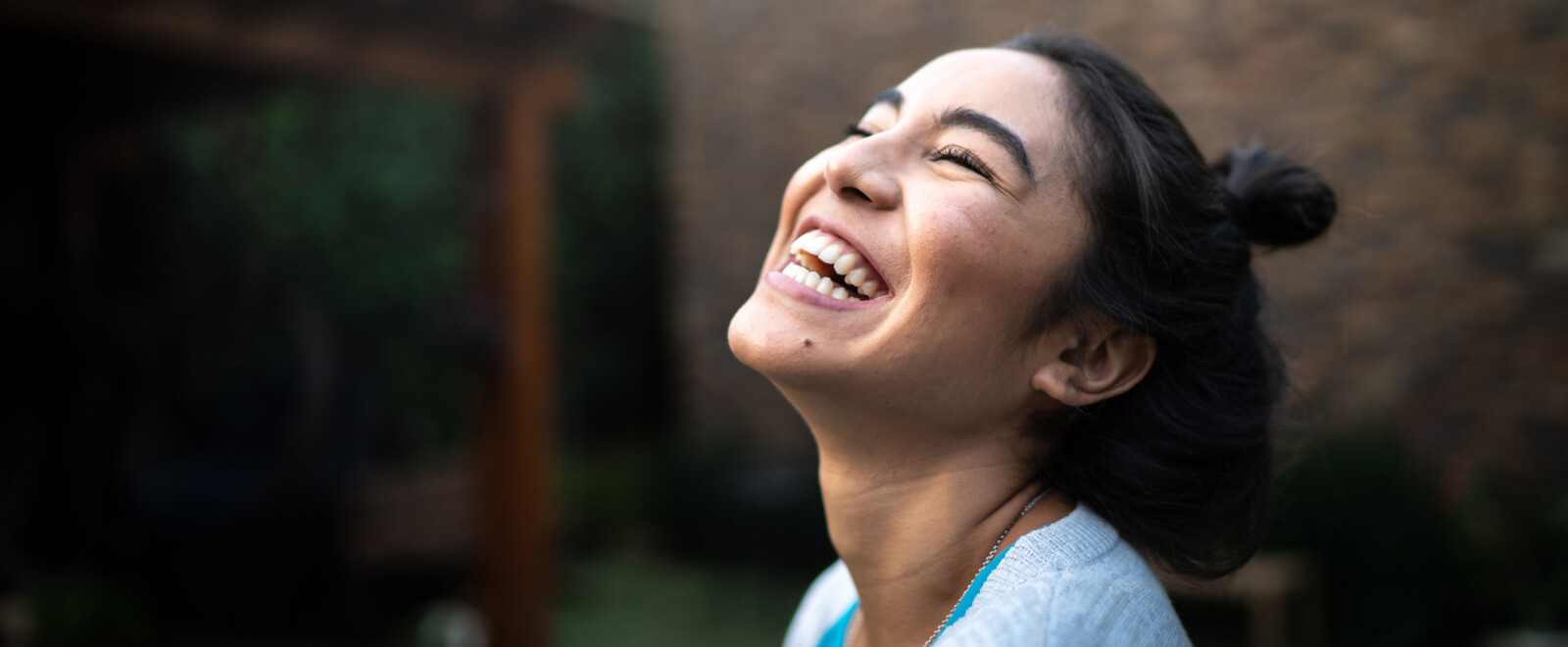 A woman laughing joyfully outdoors, capturing the uplifting impact of receiving positive feedback.