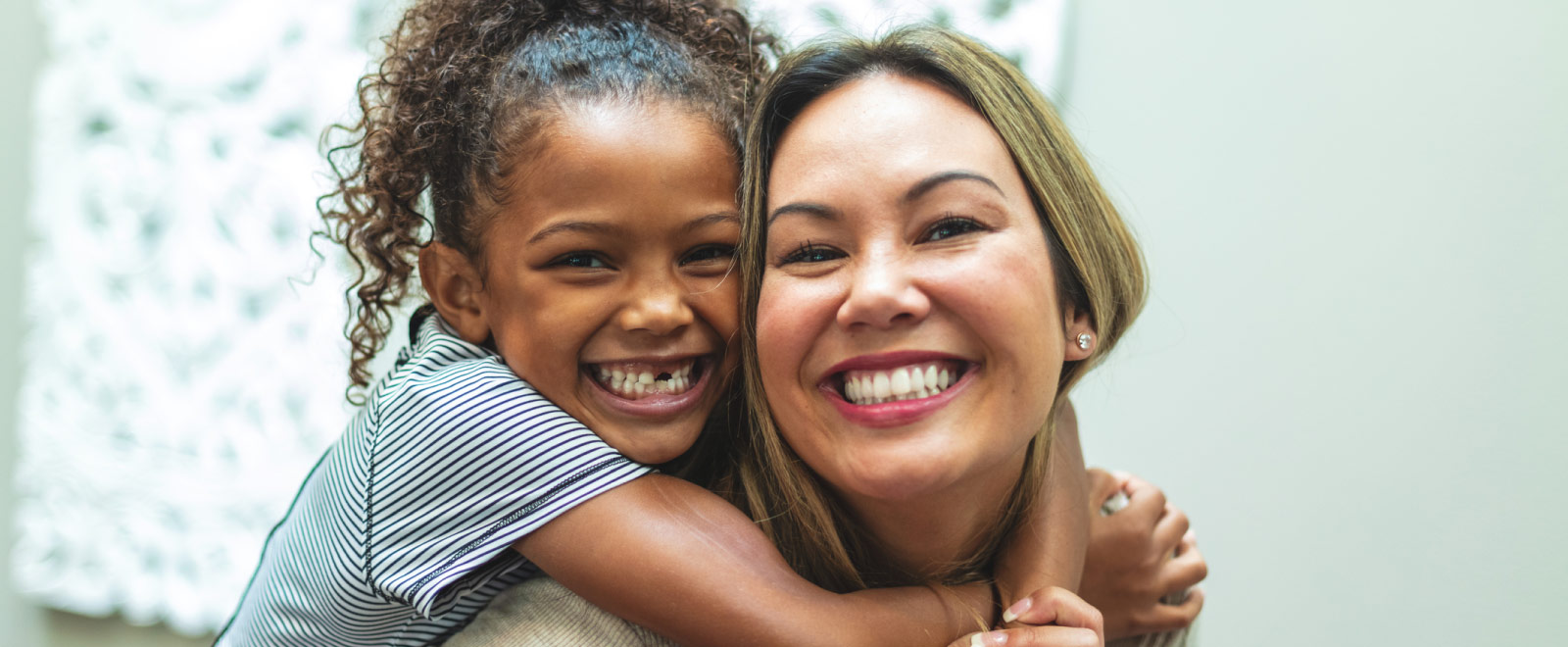 A child on a woman's back and they are both smiling.