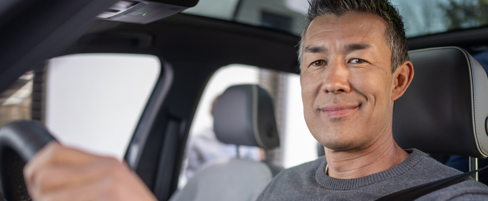 Happy man in the drivers seat of his new car.